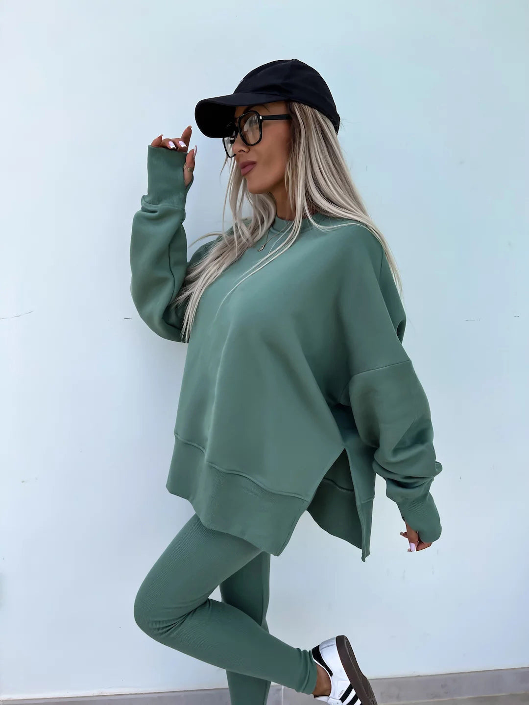 A green tracksuit with a round-neck, long and loose sweatshirt and high-elasticity slim-fit trousers. Model shows the side wearing this suit.