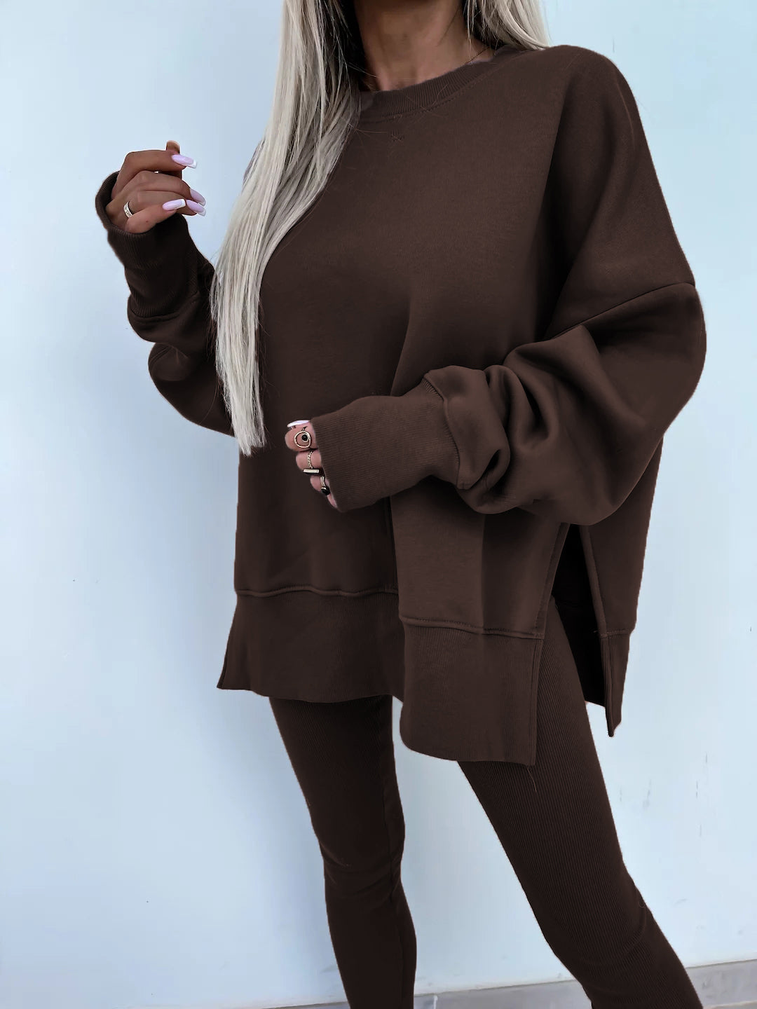 A coffee leisure suit with a round-neck, long and loose sweatshirt and high-elasticity slim-fit trousers. Model shows the front wearing this suit.