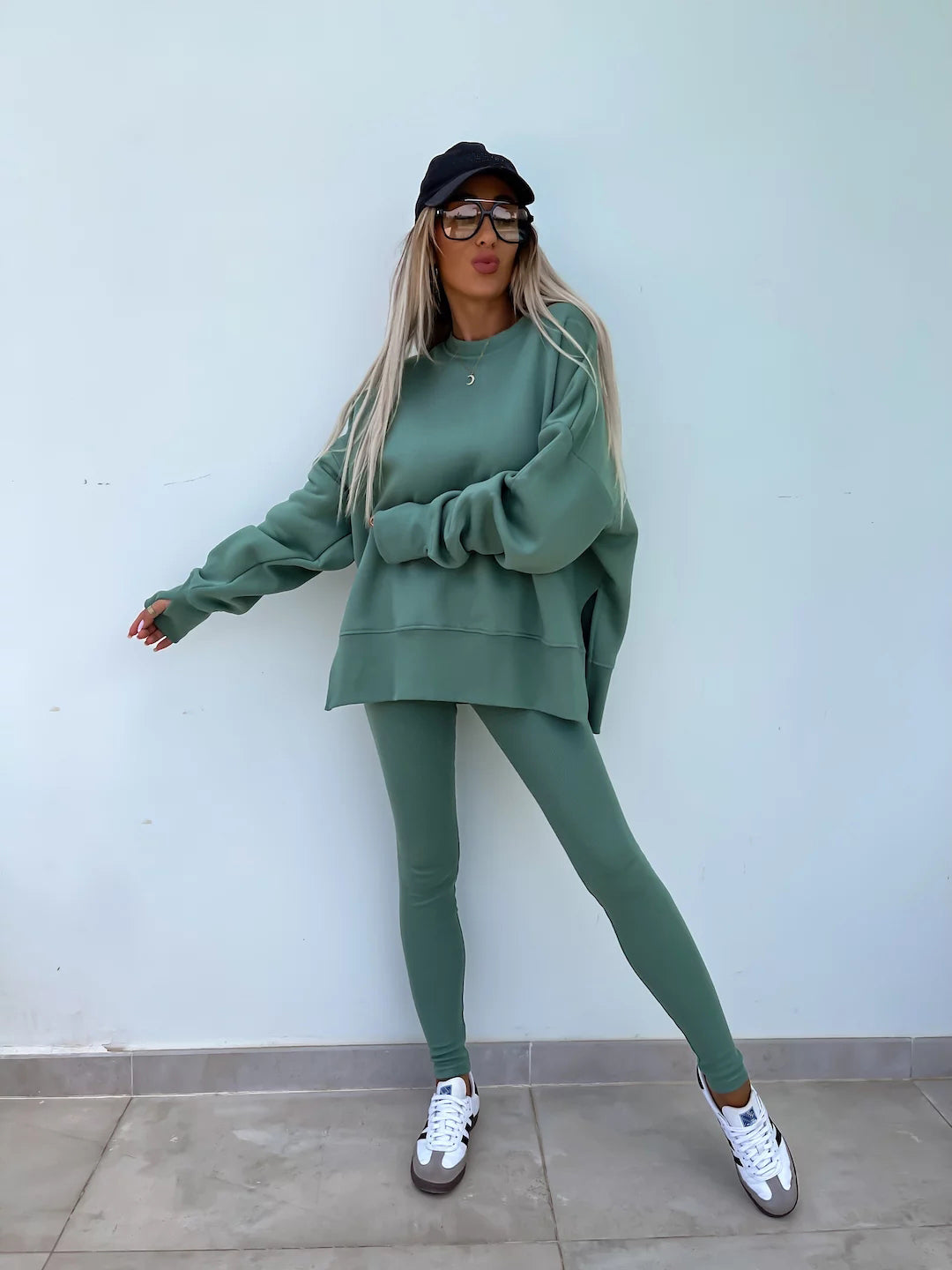 A green lounge suit with a round-neck, long and loose sweatshirt and high-elasticity slim-fit trousers. Model shows the front wearing this suit.