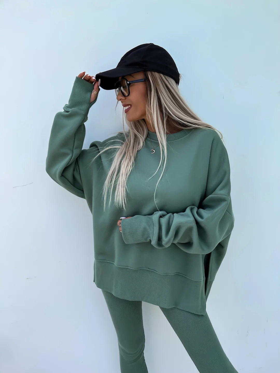 A green leisure suit with a round-neck, long and loose sweatshirt and high-elasticity slim-fit trousers. Model shows the front wearing this suit.