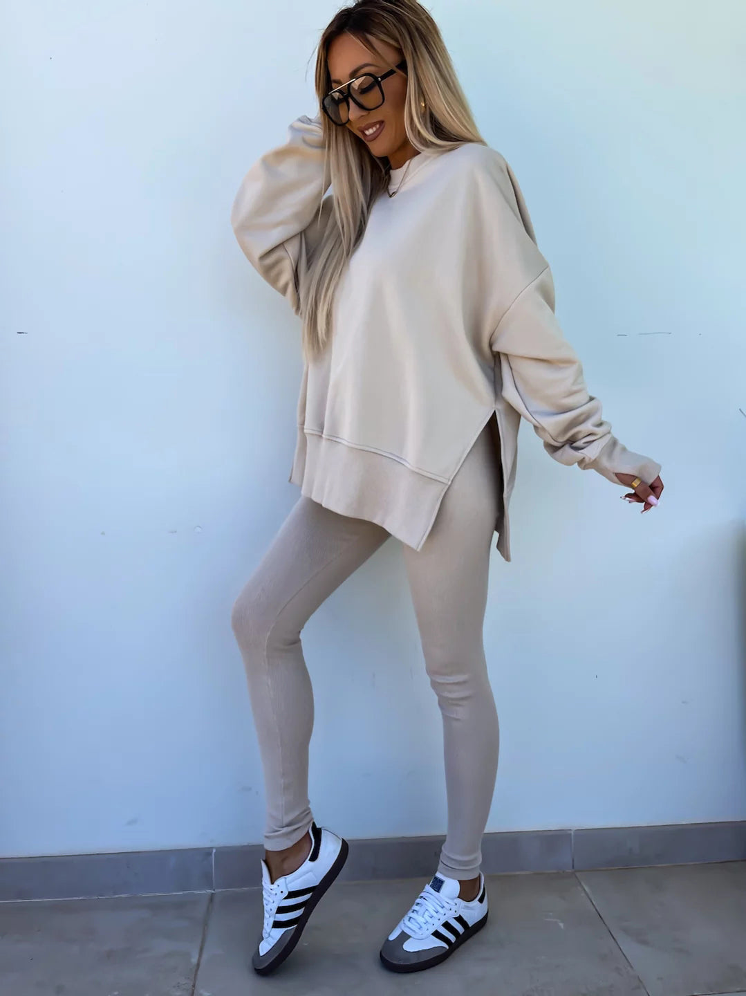 A leisure suit consisting of a round-neck, long, loose sweatshirt and high-elasticity slim-fit trousers. The model is wearing it and showing the side.