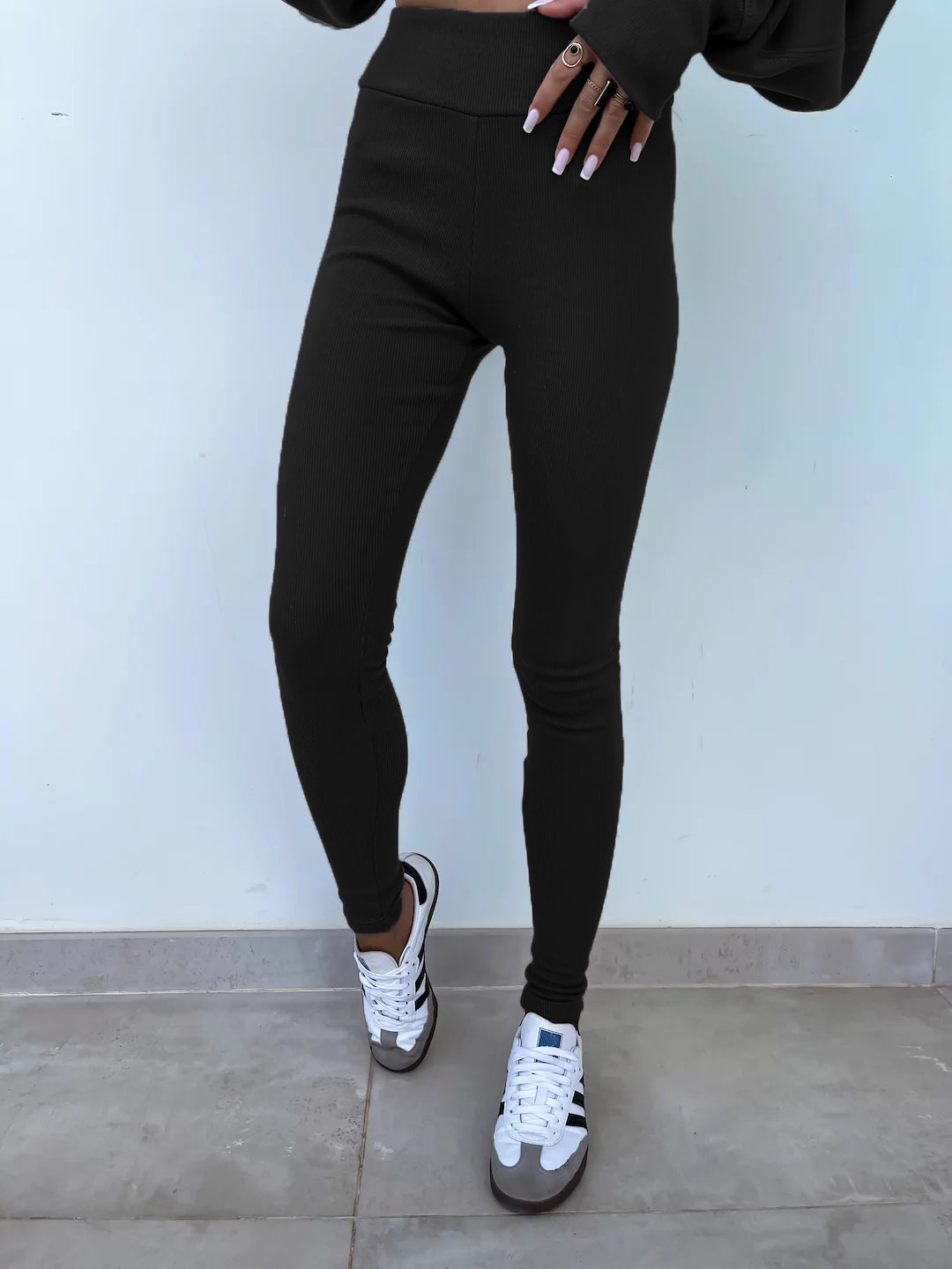Black slim-fit trousers with elastic waistband. Model is wearing for display.
