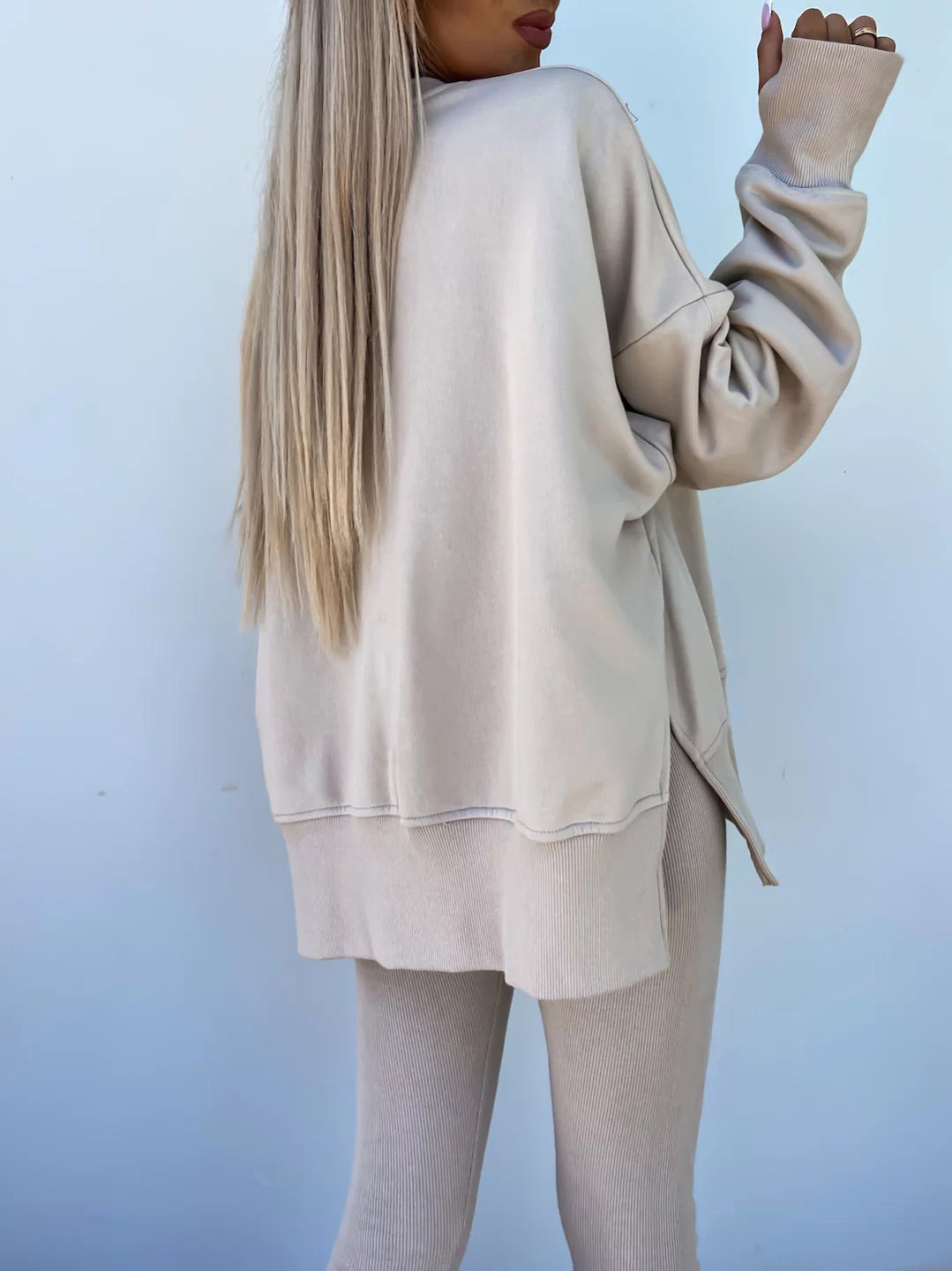 A leisure suit consisting of a round-neck, long, loose sweatshirt and high-elasticity slim-fit trousers. The model is wearing it and showing the back.