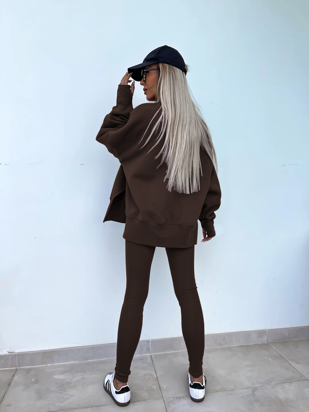 A coffee outfit with a round-neck, long and loose sweatshirt and high-elasticity slim-fit trousers. Model shows the back wearing this two piece set.
