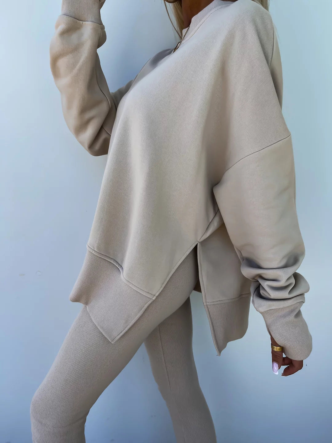 A leisure suit consisting of a round-neck, long, loose sweatshirt and high-elasticity slim-fit trousers. The model is wearing it and showing the side.