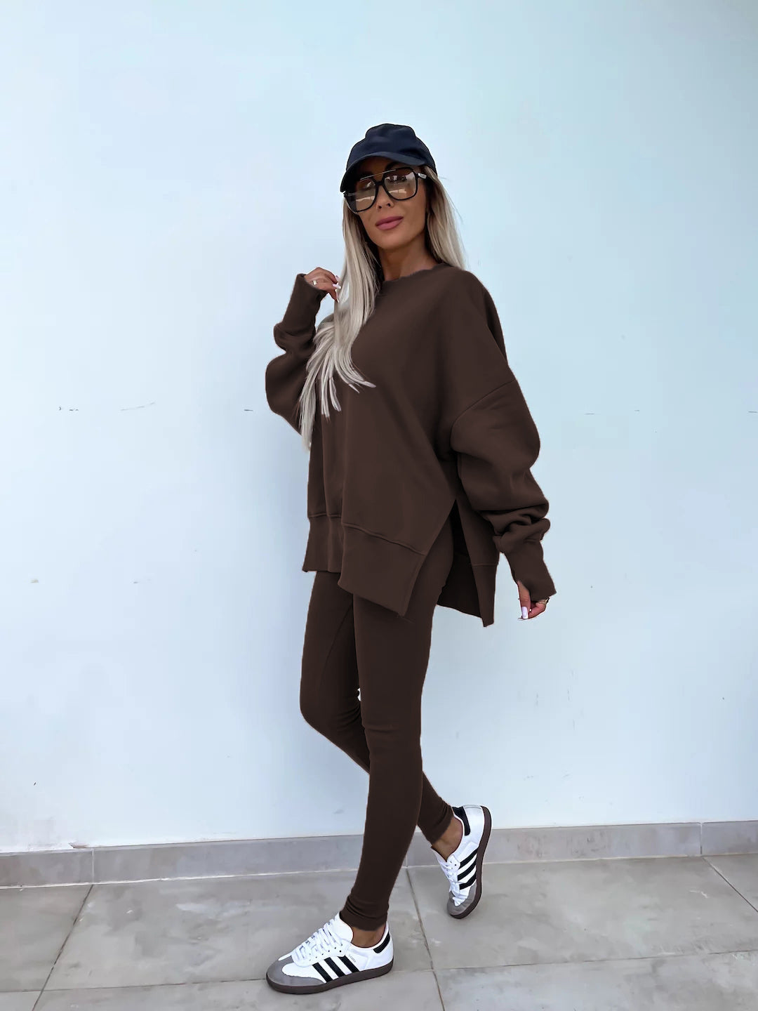 A coffee tracksuit with a round-neck, long and loose sweatshirt and high-elasticity slim-fit trousers. Model shows the side wearing this suit.